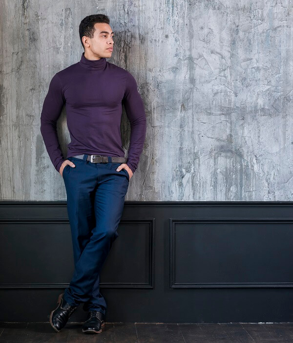 attractive young man with his hands pocket leaning concrete grey wall