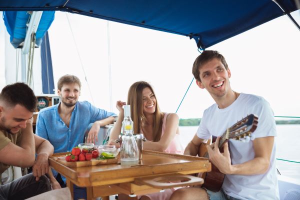 group happy friends drinking vodka cocktails playing guitar in Cruises